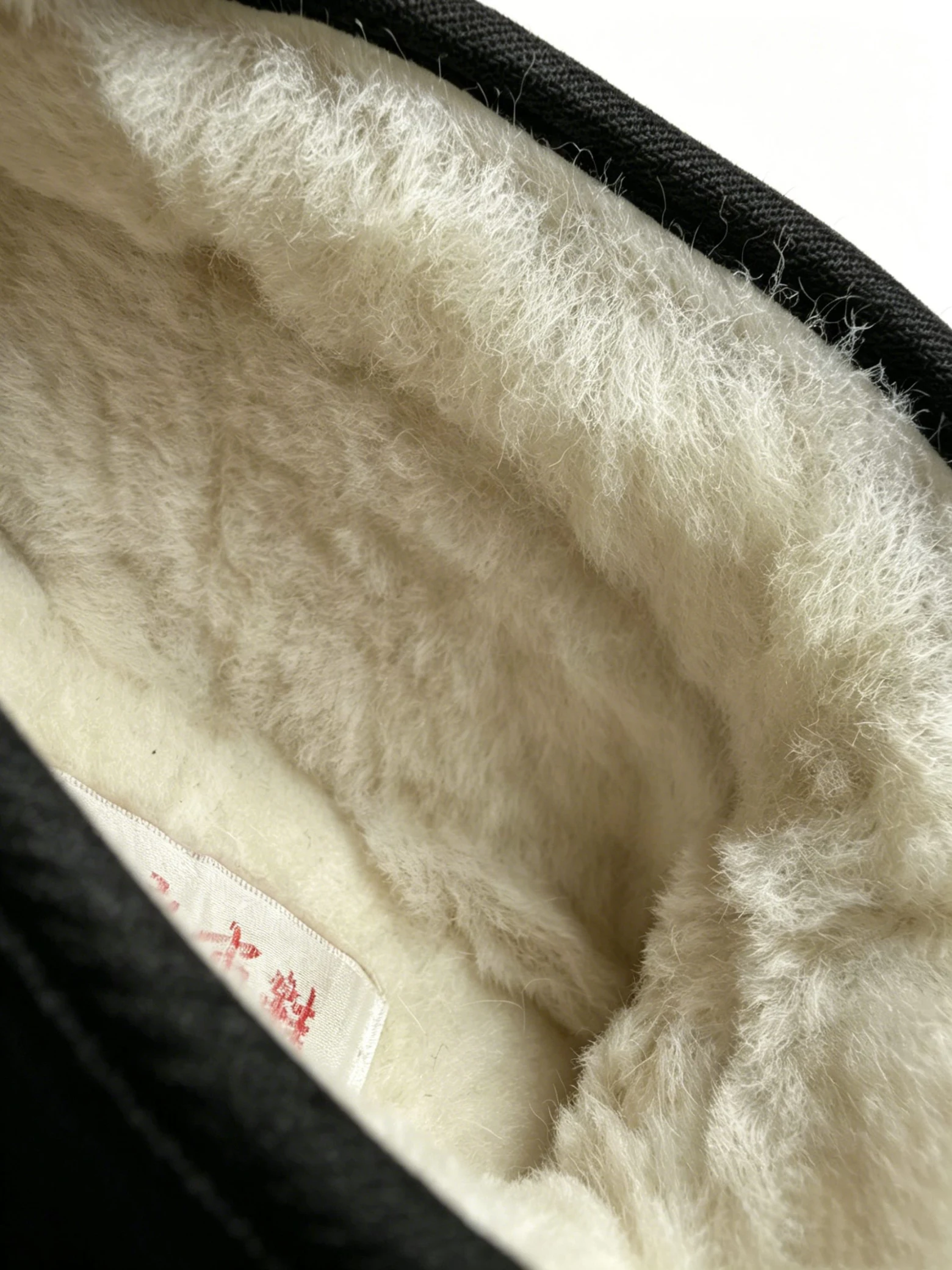 ln w**** | handmade mugwort insole cloth shoes | kardan royal fabric LUNO LN-M4014 men's high-top cotton shoes extreme close-up of interior lining - showcasing the dense, plush white faux fur texture that provides superior insulation and softness against the foot; the thick pile contrasts with the black fabric upper edge visible at the top left, emphasizing the shoe's cozy, winter-ready construction designed for maximum warmth in cold weather.