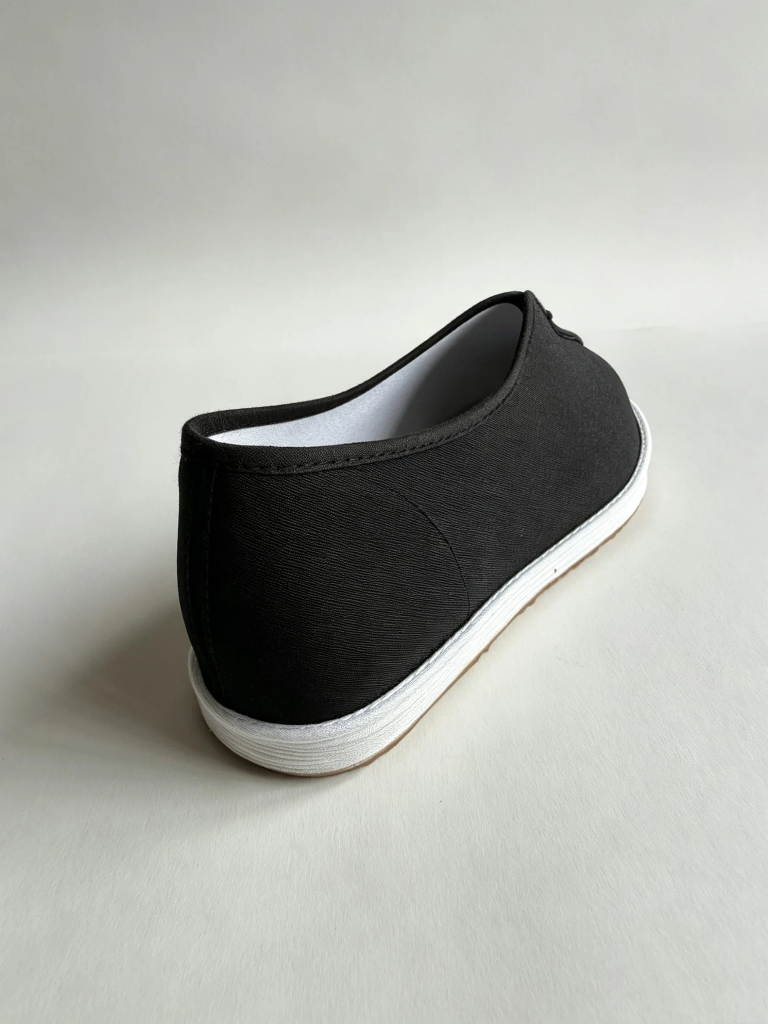 luno ln m5025 traditional chinese cloth shoes yellow ox tendon outsole LUNO LN-M5025 traditional Chinese cloth shoes rear-side view - featuring a sleek black canvas upper with elastic side panels for easy slip-on wear, and a white layered rubber sole; the interior reveals a quilted insole with embroidered mugwort leaves and red "Beijing Cloth Shoes" characters, emphasizing herbal comfort and cultural craftsmanship.